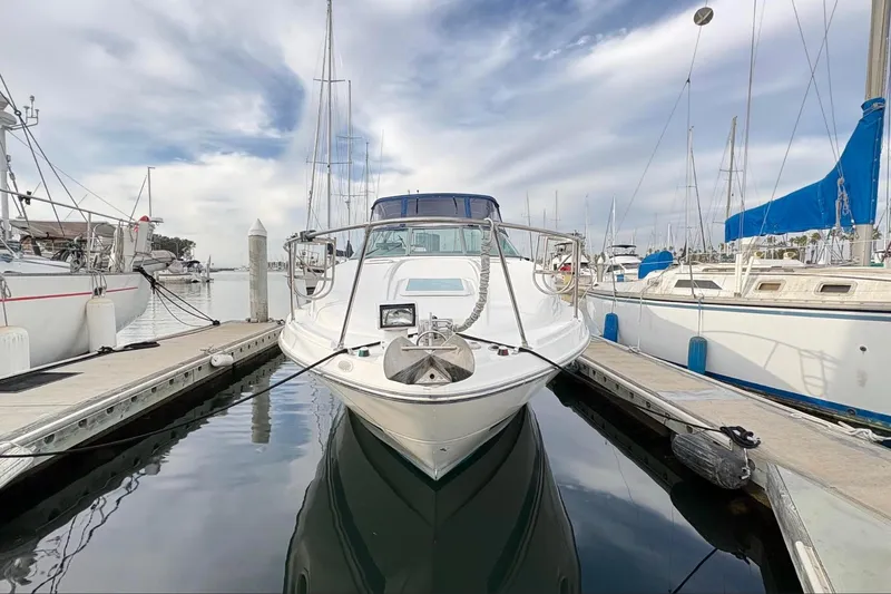 Slide: The Image of 2007 Bayliner 285 boat docked at marina, surrounded by sailboats under a cloudy sky. - 2