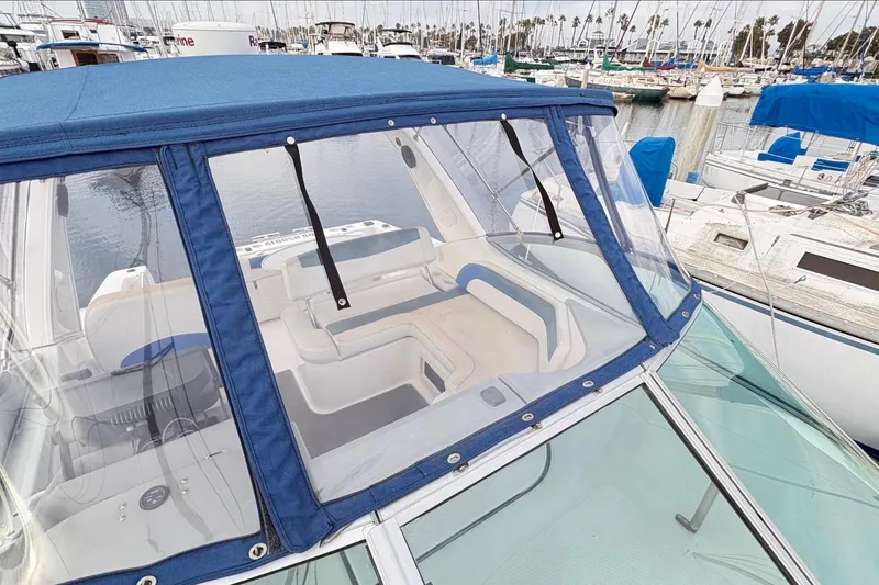 Slide: The Image of 2007 Bayliner 285 boat with blue canopy, docked in a marina. - 4