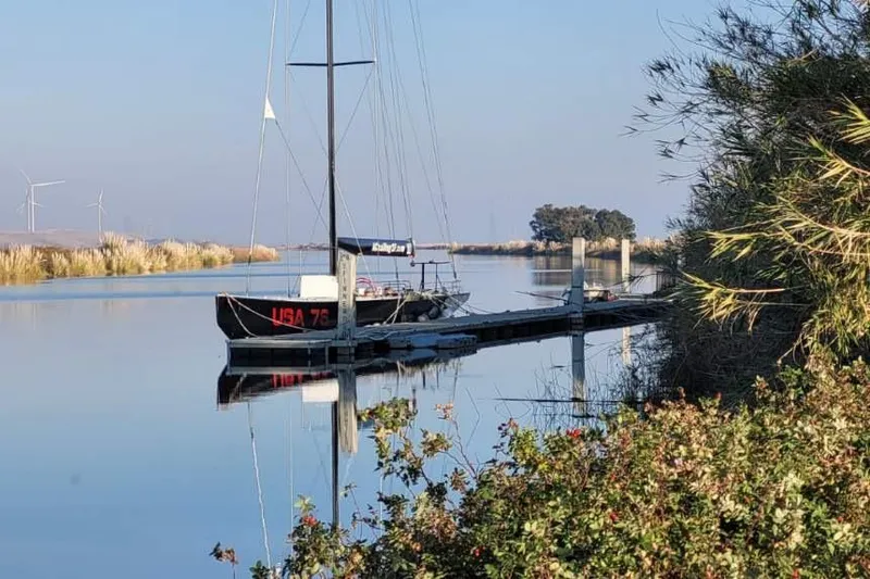 Slide: The Image of Sailboat "USA 76" docked on calm water, surrounded by nature, 2002 International Americas Cup Class. - 20