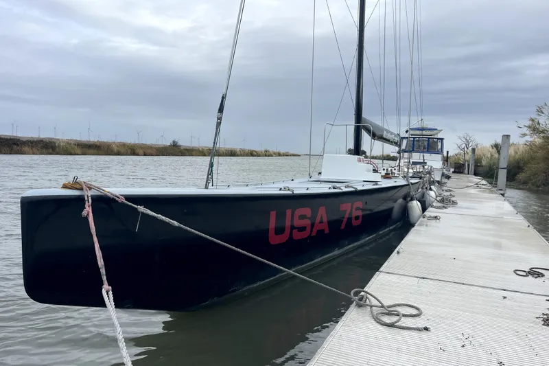 Slide: The Image of Sleek 2002 Custom International Americas Cup Class yacht "USA 76" docked by a riverbank. - 3