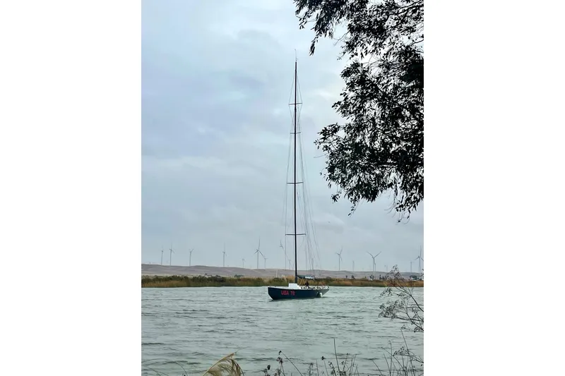 Slide: The Image of Sailboat on a river with wind turbines in the background, 2002 International Americas Cup Class. - 5
