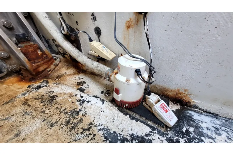 Slide: The Image of Bilge pump setup on 2002 Custom International Americas Cup Class boat, showing rust and wear. - 59