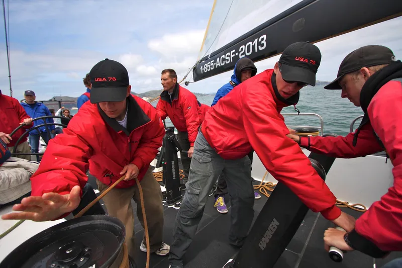 Slide: The Image of Crew members in red jackets operating winches on a 2002 International Americas Cup Class yacht. - 9