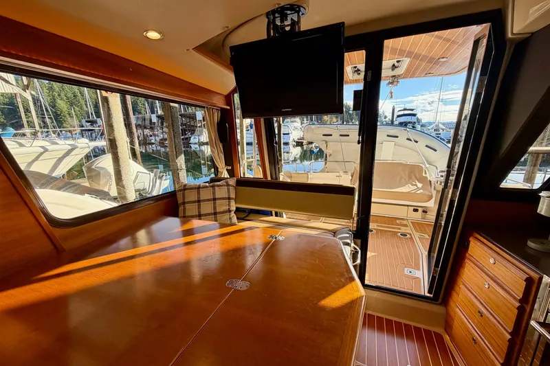 Slide: The Image of Interior of 2018 Ranger Tugs R-29 CB with wooden table, TV, and marina view. - 23