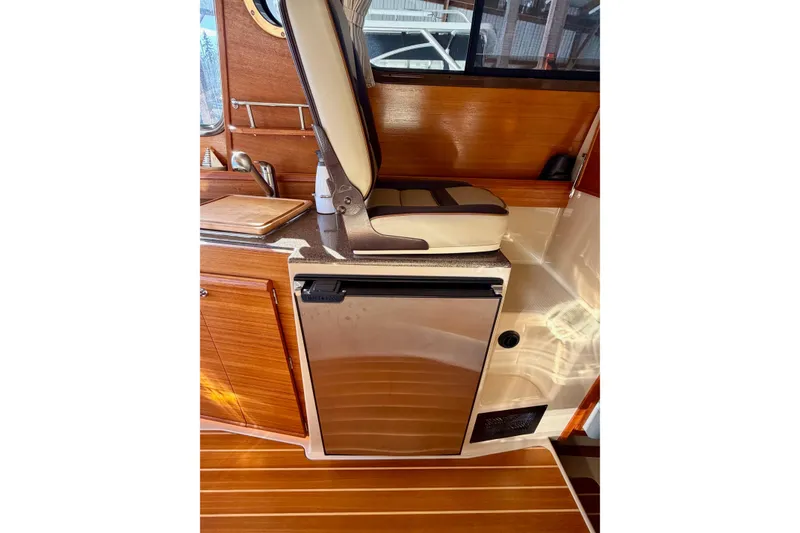 Slide: The Image of 2018 Ranger Tugs R-29 CB interior with wooden cabinetry and compact fridge. - 43