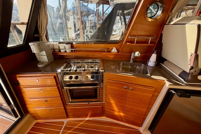 Slide: The Image of 2018 Ranger Tugs R-29 CB galley with stove, sink, and wooden cabinetry. - 45