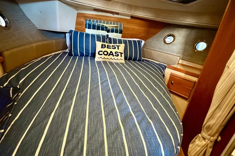 Slide: The Image of 2018 Ranger Tugs R-29 CB cabin with striped bedding and "Best Coast" pillow. - 51