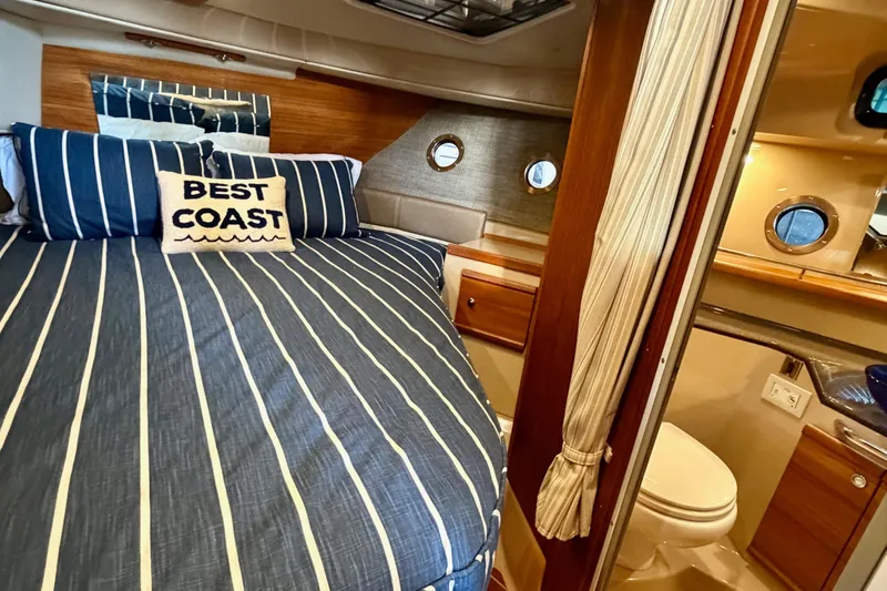 Slide: The Image of 2018 Ranger Tugs R-29 CB cabin interior with striped bedding and nautical decor. - 52