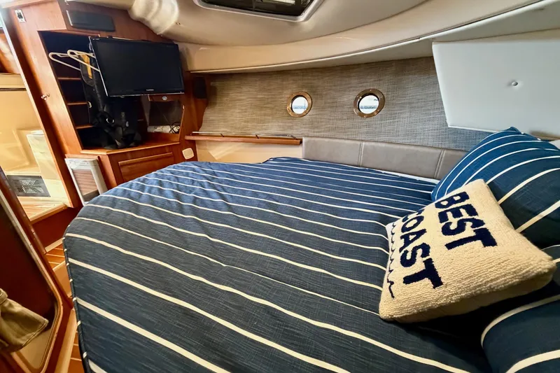 Slide: The Image of 2018 Ranger Tugs R-29 CB cabin interior with striped bedding and "Best Coast" pillow. - 53