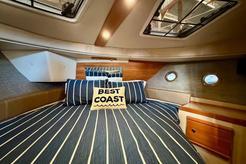 Slide: The Image of 2018 Ranger Tugs R-29 CB cabin with striped bedding and "Best Coast" pillow. - 54
