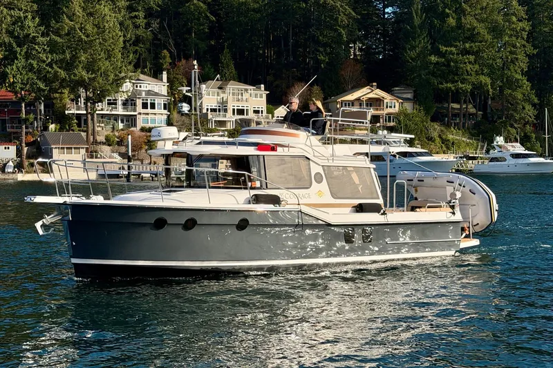 Slide: The Image of 2018 Ranger Tugs R-29 CB cruising on a scenic waterfront with houses and trees. - 7
