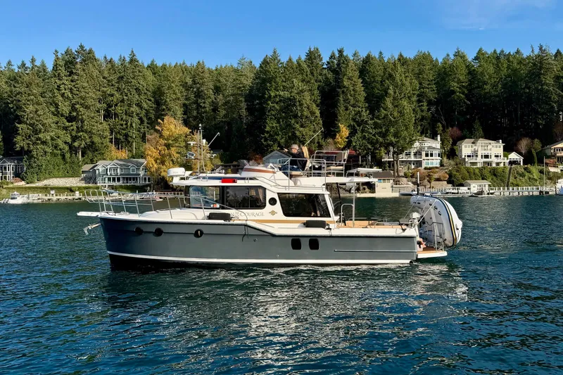 Slide: The Image of 2018 Ranger Tugs R-29 CB boat cruising on a scenic lake with forested shoreline. - 8