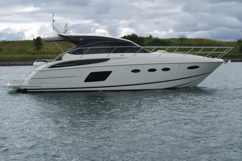 The Image of 2015 Princess V48 yacht on serene water near a sandy shoreline. - 0