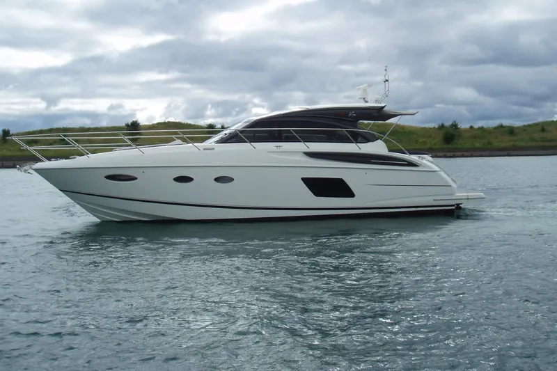 Slide: The Image of 2015 Princess V48 yacht cruising on a calm, scenic waterway under cloudy skies. - 3