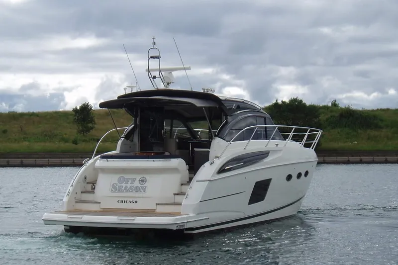 Slide: The Image of 2015 Princess V48 yacht cruising on a calm waterway under cloudy skies. - 6