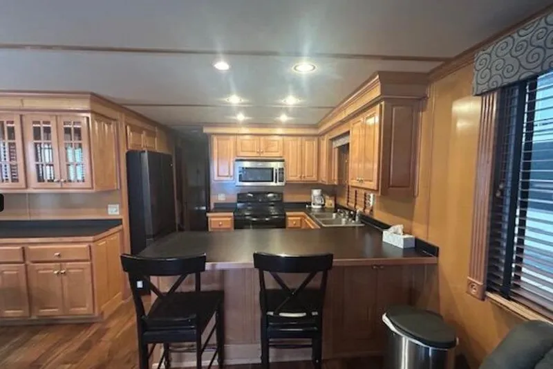 Slide: The Image of 2007 Sumerset Lakeview HD kitchen with wooden cabinets, black countertops, and modern appliances. - 14