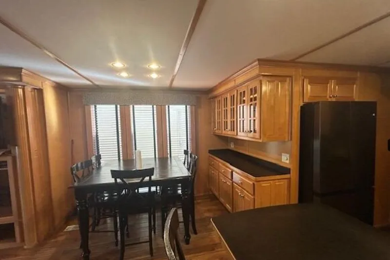 Slide: The Image of 2007 Sumerset Lakeview HD kitchen with wooden cabinets, dining table, and black appliances. - 15