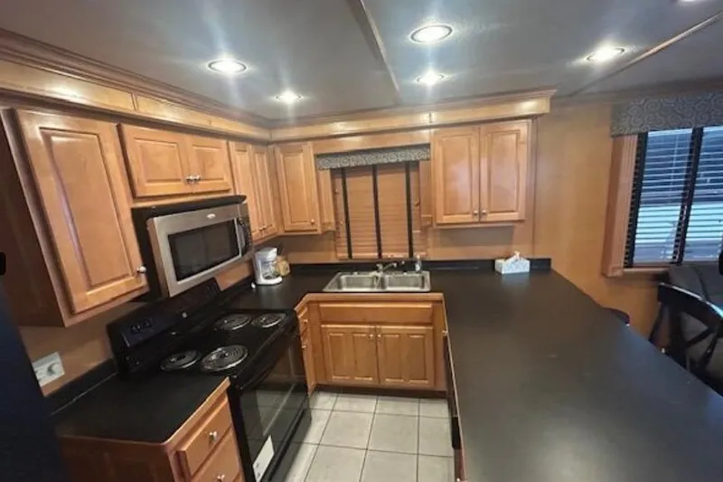 Slide: The Image of 2007 Sumerset Lakeview HD kitchen with wooden cabinets, black countertops, and modern appliances. - 16