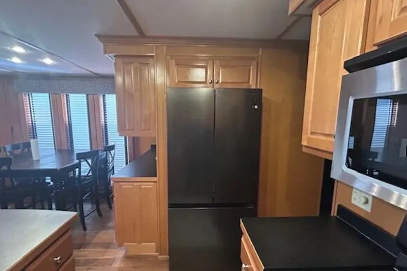 Slide: The Image of Kitchen interior of 2007 Sumerset Lakeview HD with wooden cabinets and black appliances. - 17