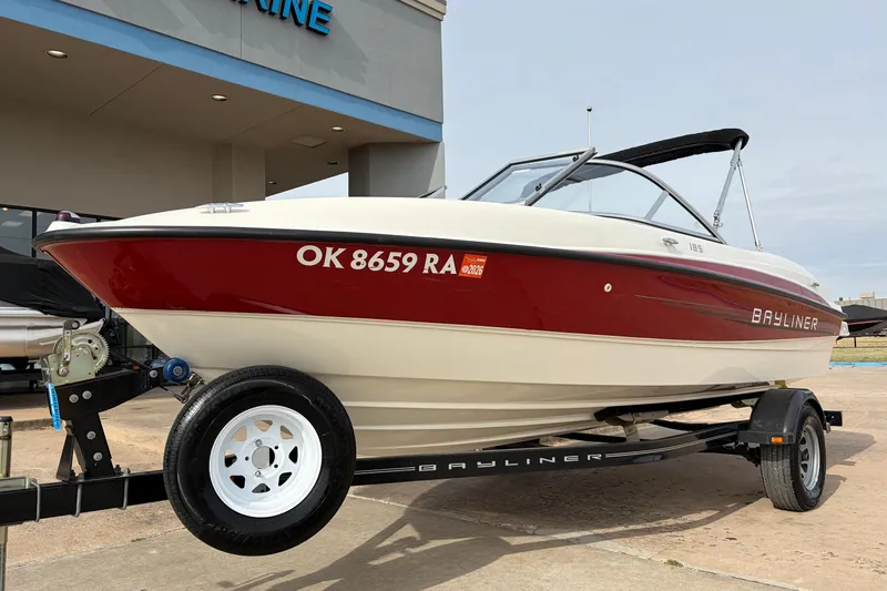 Slide: The Image of 2011 Bayliner 185 boat on trailer, red and white, parked outside dealership. - 2
