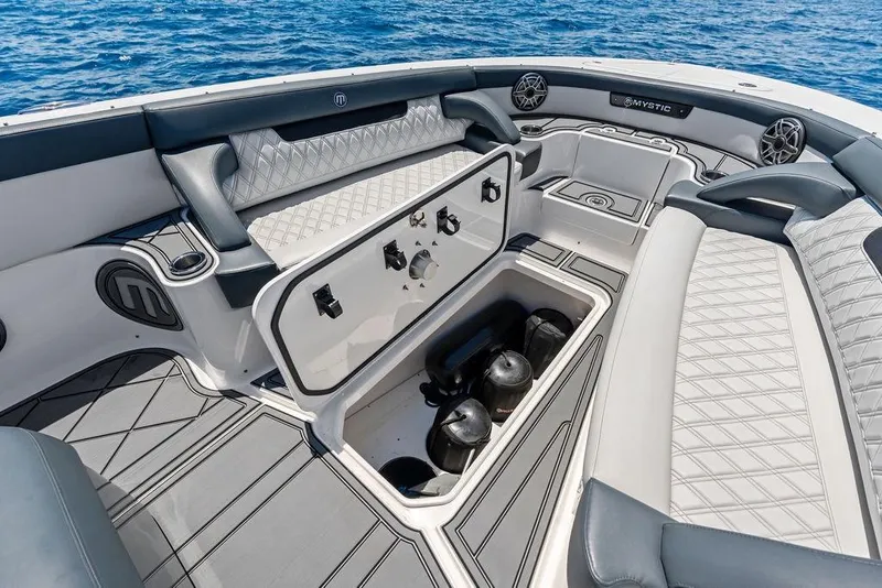 Slide: The Image of Luxurious 2020 Mystic M4200 boat interior with storage compartment, diamond-stitched seating, and ocean backdrop. - 16