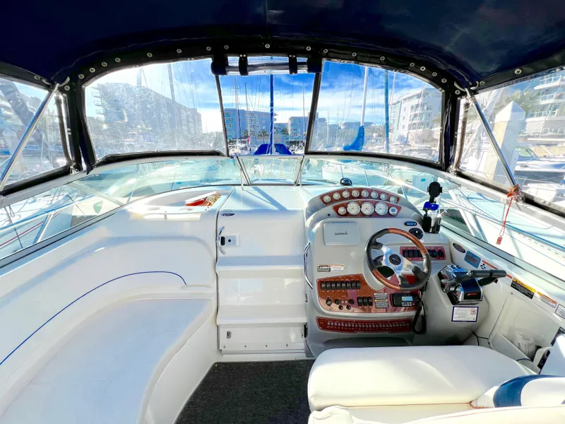 Slide: The Image of 2008 Bayliner 320 boat cockpit with steering wheel, gauges, and seating in marina setting. - 22
