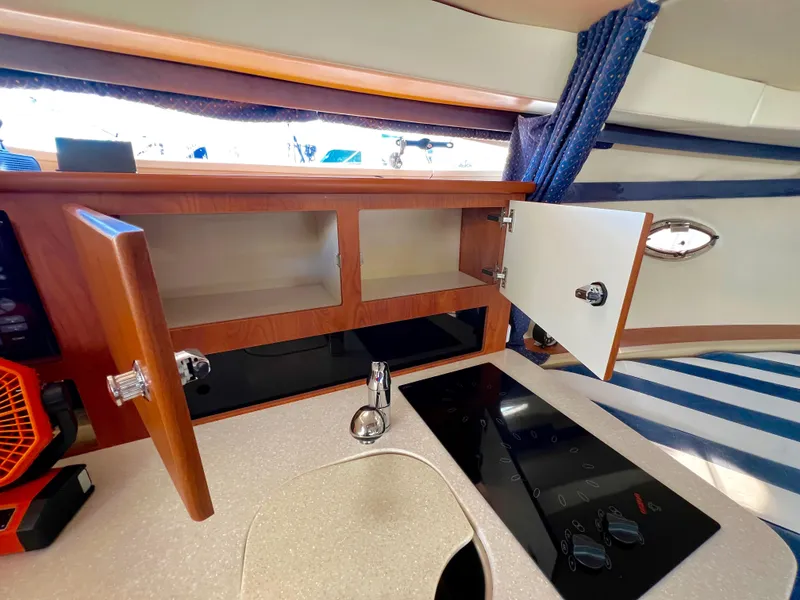 Slide: The Image of 2008 Bayliner 320 yacht kitchen with sink, stovetop, and wooden cabinetry. - 40