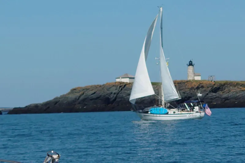 Slide: The Image of Sailboat Pacific Seacraft 37 (1982) cruising near rocky island with lighthouse. - 1