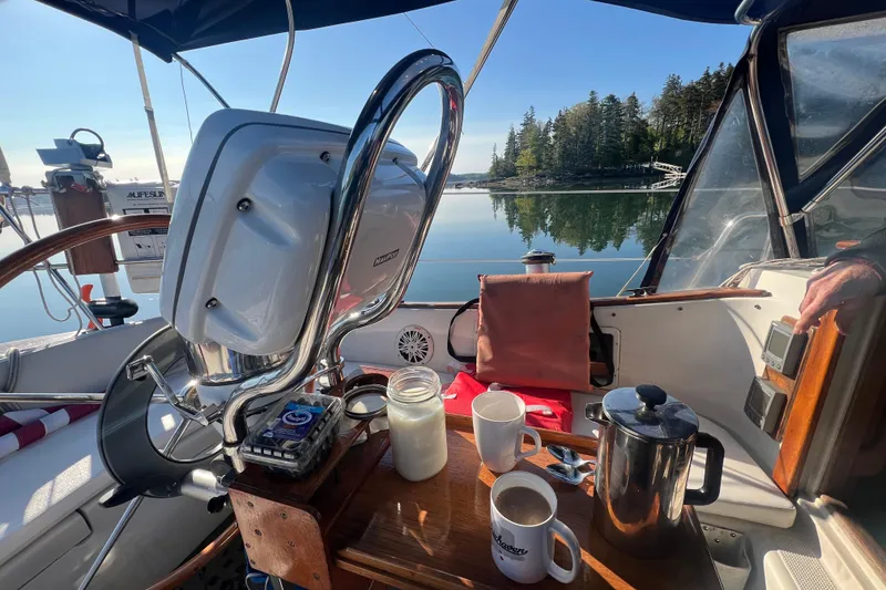 Slide: The Image of Cockpit of 1982 Pacific Seacraft 37 with coffee setup, overlooking serene waters and trees. - 19