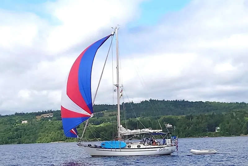 Slide: The Image of 1982 Pacific Seacraft 37 sailboat with colorful spinnaker on a scenic lake. - 2