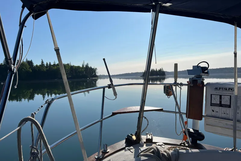 Slide: The Image of Sailboat view from 1982 Pacific Seacraft 37, serene lake and forest backdrop. - 21