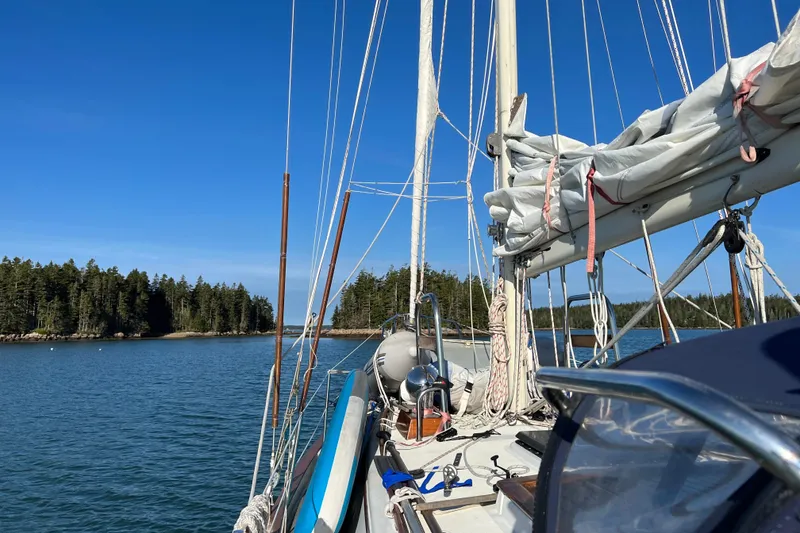 Slide: The Image of Sailboat Pacific Seacraft 37, 1982 model, anchored near forested shoreline under clear blue sky. - 27