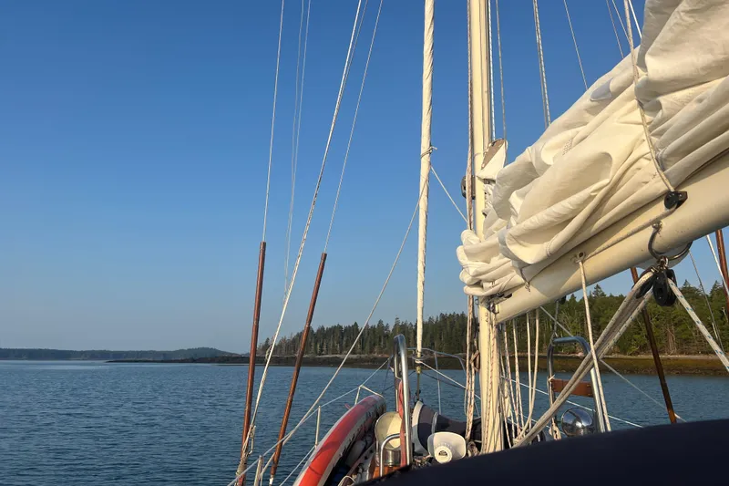 Slide: The Image of Sailing on a 1982 Pacific Seacraft 37, calm waters, clear blue sky, forested shoreline. - 29