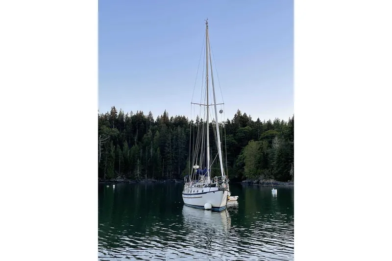 Slide: The Image of Sailboat Pacific Seacraft 37, 1982 model, anchored in a serene forested bay. - 3