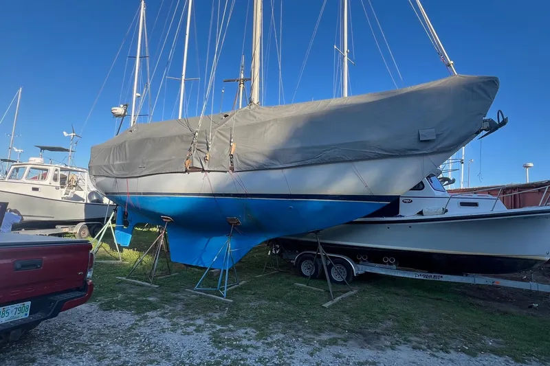 Slide: The Image of 1982 Pacific Seacraft 37 sailboat on trailer, covered, with blue hull, in boatyard. - 6