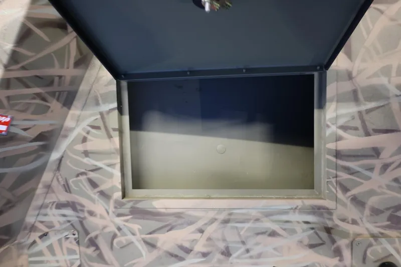 Slide: The Image of Open storage compartment on 2026 Lund 1870 Predator CC boat with camouflage pattern. - 13