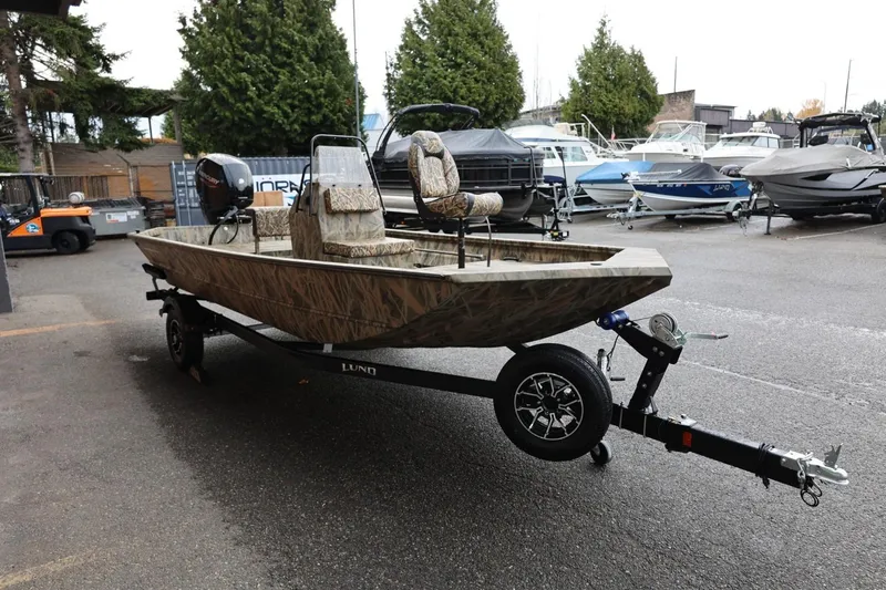 Slide: The Image of 2026 Lund 1870 Predator CC boat on trailer, camo design, parked outdoors. - 28