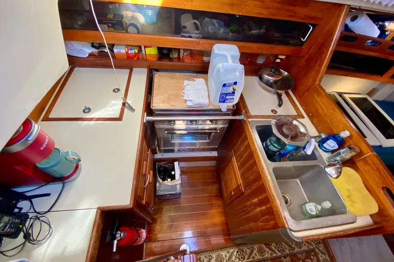 Slide: The Image of Compact kitchen in a 1987 O'Day 34 sailboat with wooden cabinetry and modern appliances. - 14
