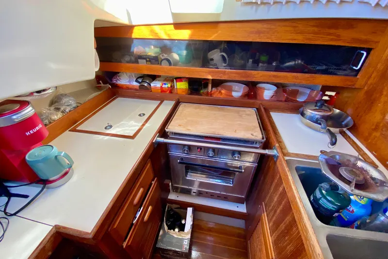 Slide: The Image of 1987 O'Day 34 sailboat galley with stove, sink, and storage shelves. - 16