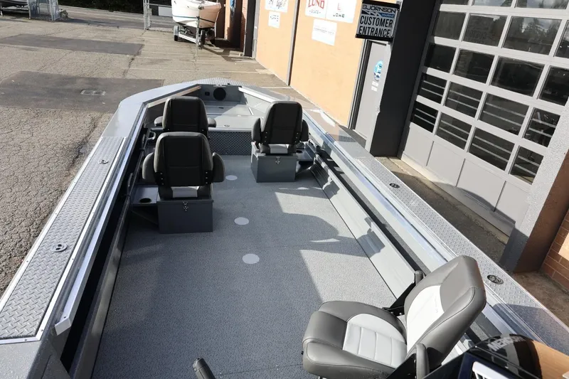 Slide: The Image of 2026 Thunder Jet 229 Rush OT boat interior with four seats, parked outside a garage. - 15