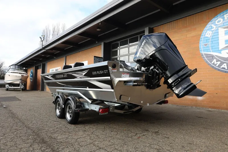 Slide: The Image of 2026 Thunder Jet 229 Rush OT boat with powerful outboard motor, parked outside a showroom. - 4