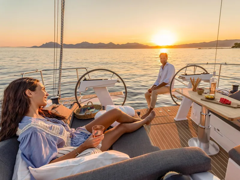 Slide: The Image of Couple relaxing on 2025 Hanse 410 yacht at sunset, enjoying drinks and ocean view. - 17