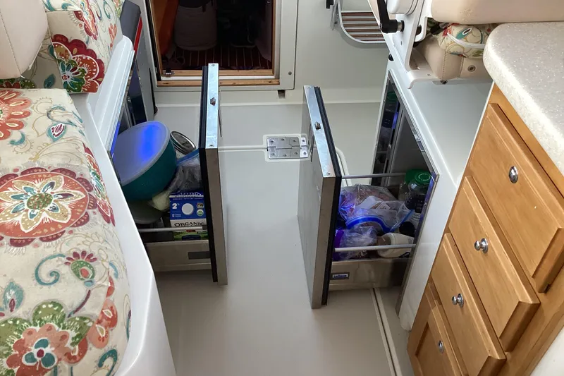 Slide: The Image of Interior of a 2008 Back Cove 33 boat with open storage drawers and floral seating. - 21