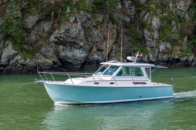 Slide: The Image of 2008 Back Cove 33 boat cruising near rocky shoreline. - 5