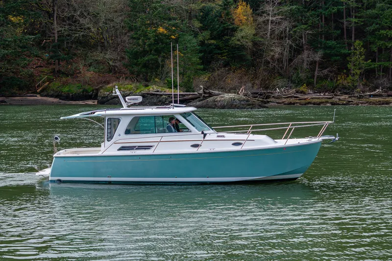 Slide: The Image of 2008 Back Cove 33 boat cruising on a serene, forest-lined waterway. - 6