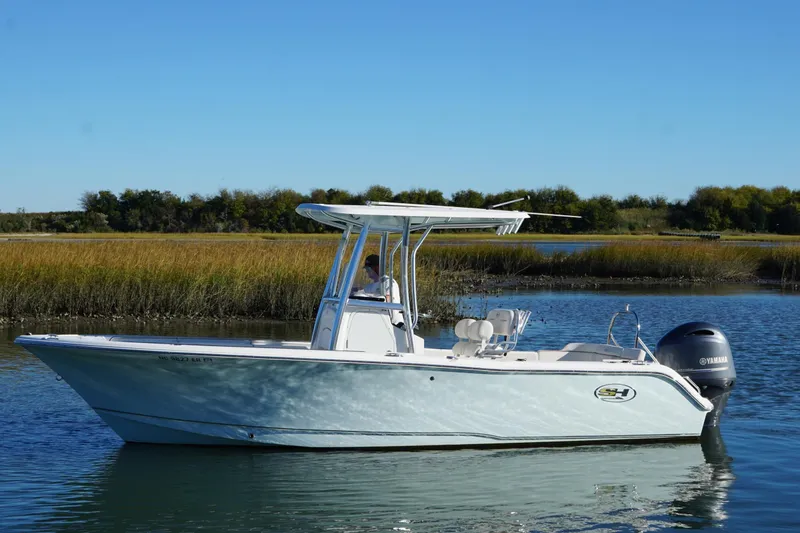 The Image of 2021 Sea Hunt Ultra 229 boat cruising on a calm river with lush greenery. - 1