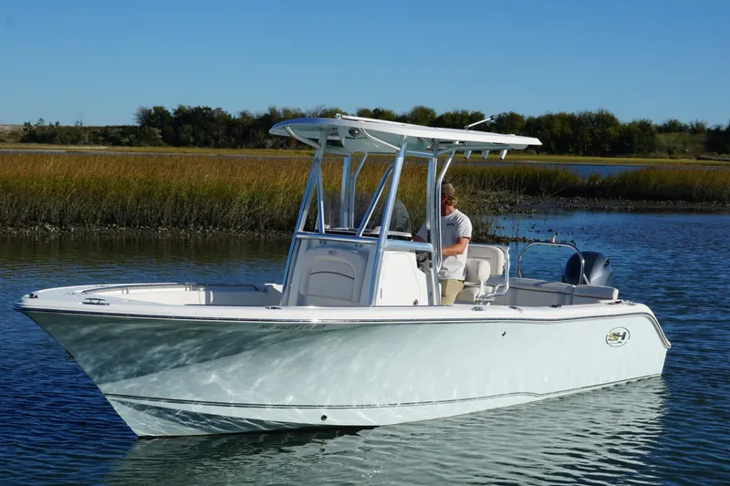 Slide: The Image of 2021 Sea Hunt Ultra 229 boat cruising on a calm lake with a clear blue sky. - 7