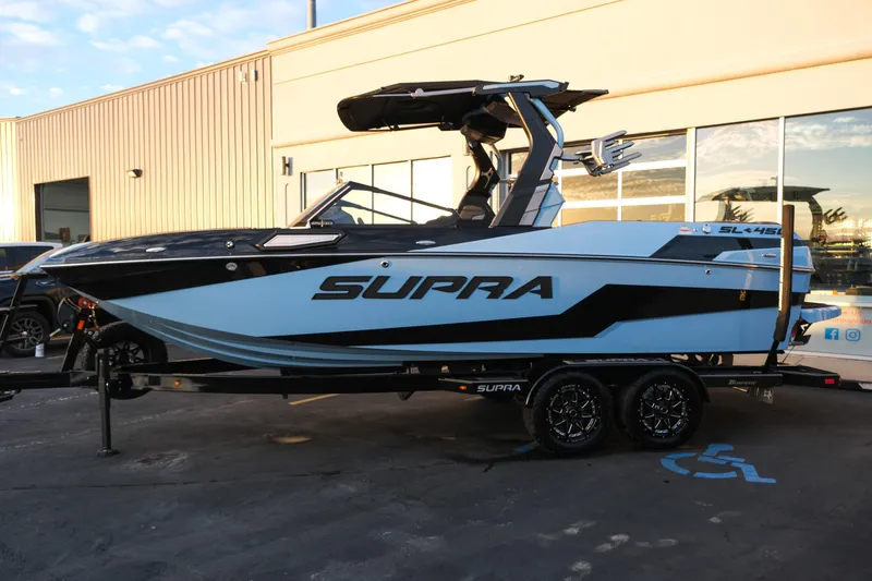 Slide: The Image of 2024 Supra SL boat on trailer, parked outside a building. - 1