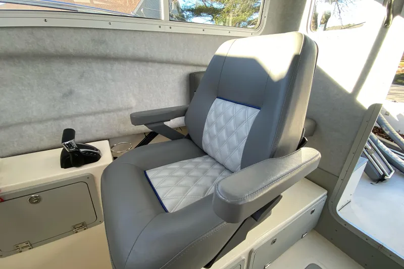Slide: The Image of 2023 Defiance Admiral 250 EX boat interior with a cushioned captain's chair and control panel. - 4