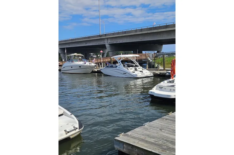 Slide: The Image of 2024 Yamaha Boats 275SD docked near a bridge on a sunny day. - 8
